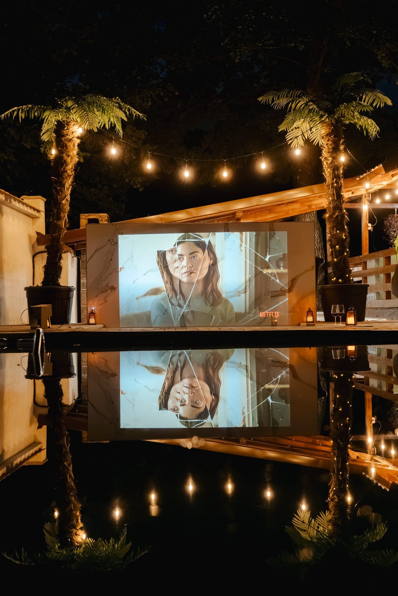 Ecranul de cinema reflectat seara în apa piscinei la Villa Palm