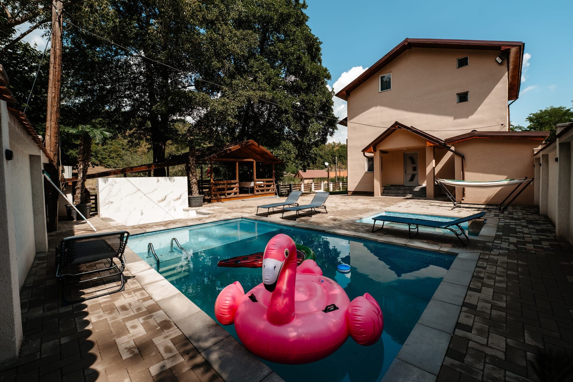 Villa Palm văzută din curte, cu piscină și șezlonguri, Poiana Aiudului